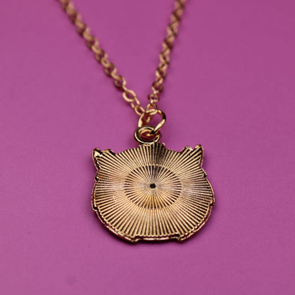 Gold necklace with a decorative pendant on a pink background