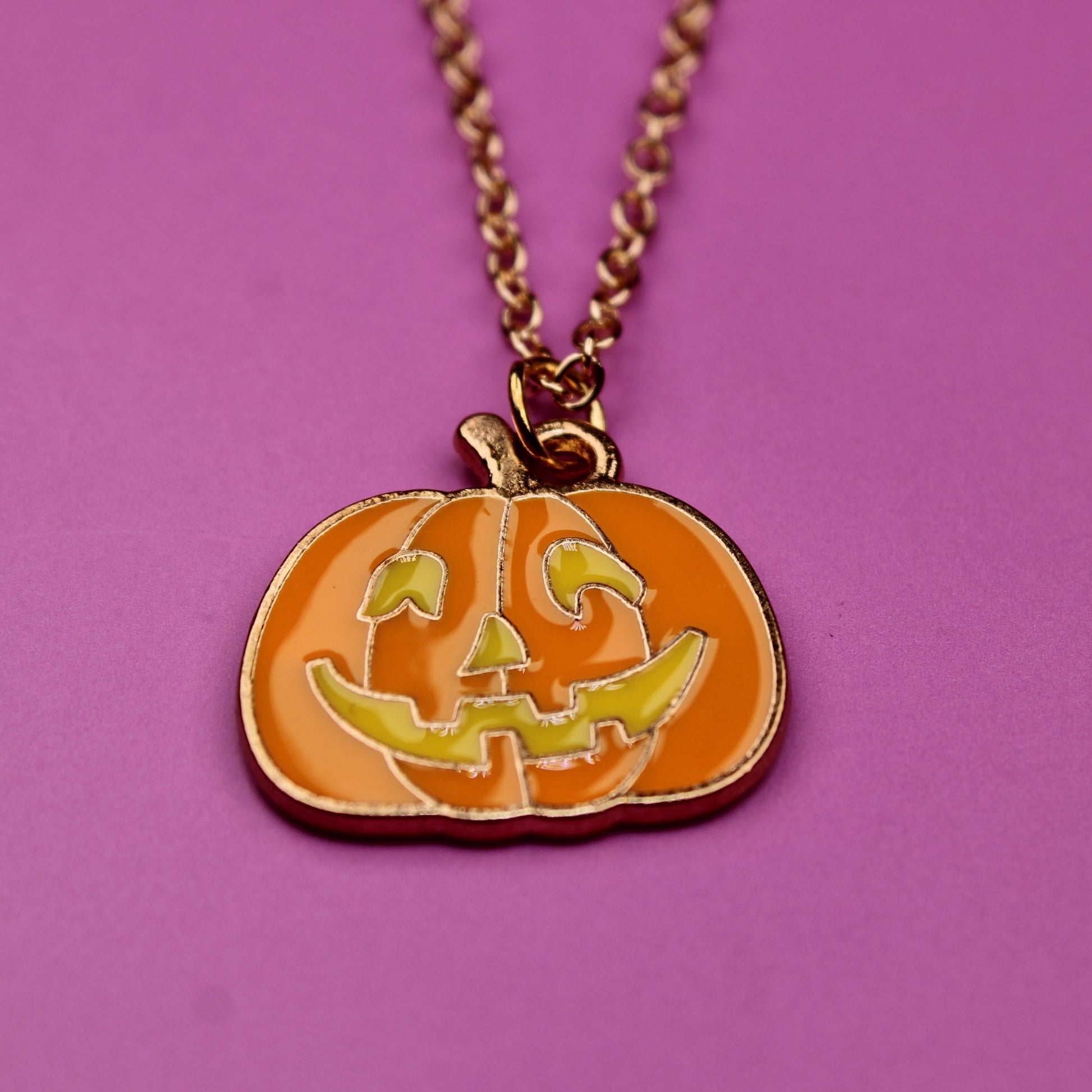 Pumpkin-shaped pendant necklace on a pink background