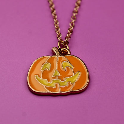 Pumpkin-shaped pendant necklace on a pink background