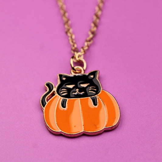 Pumpkin necklace with a black cat design on a pink background
