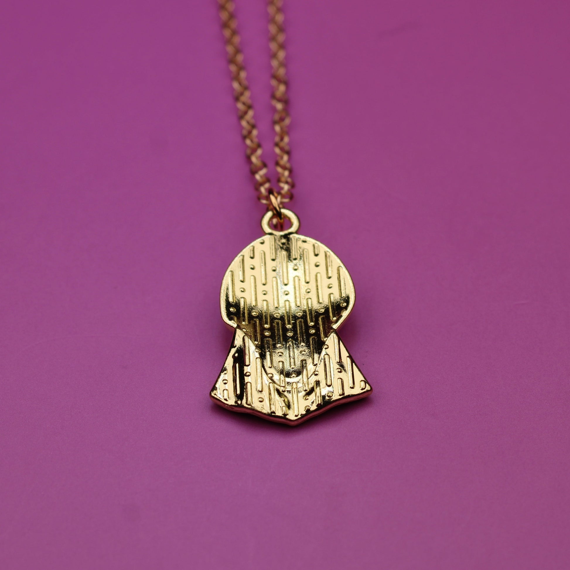 Gold necklace with a pendant on a purple background