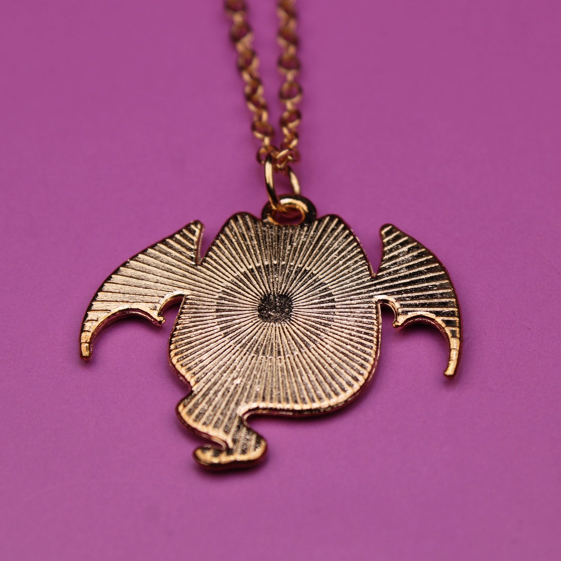 Gold necklace with a unique pendant on a purple background