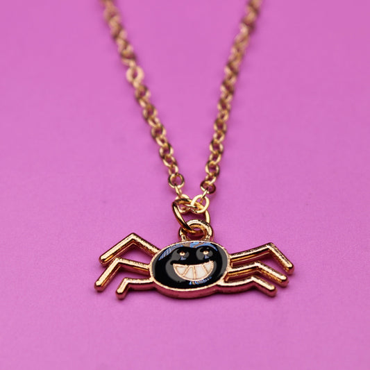Spider-shaped pendant necklace on a pink background