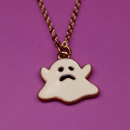 Ghost-shaped pendant on a chain against a purple background