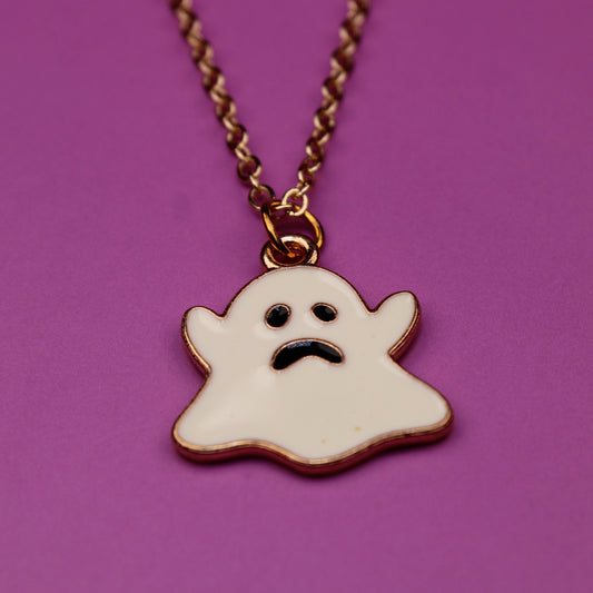 Ghost-shaped pendant on a chain against a purple background
