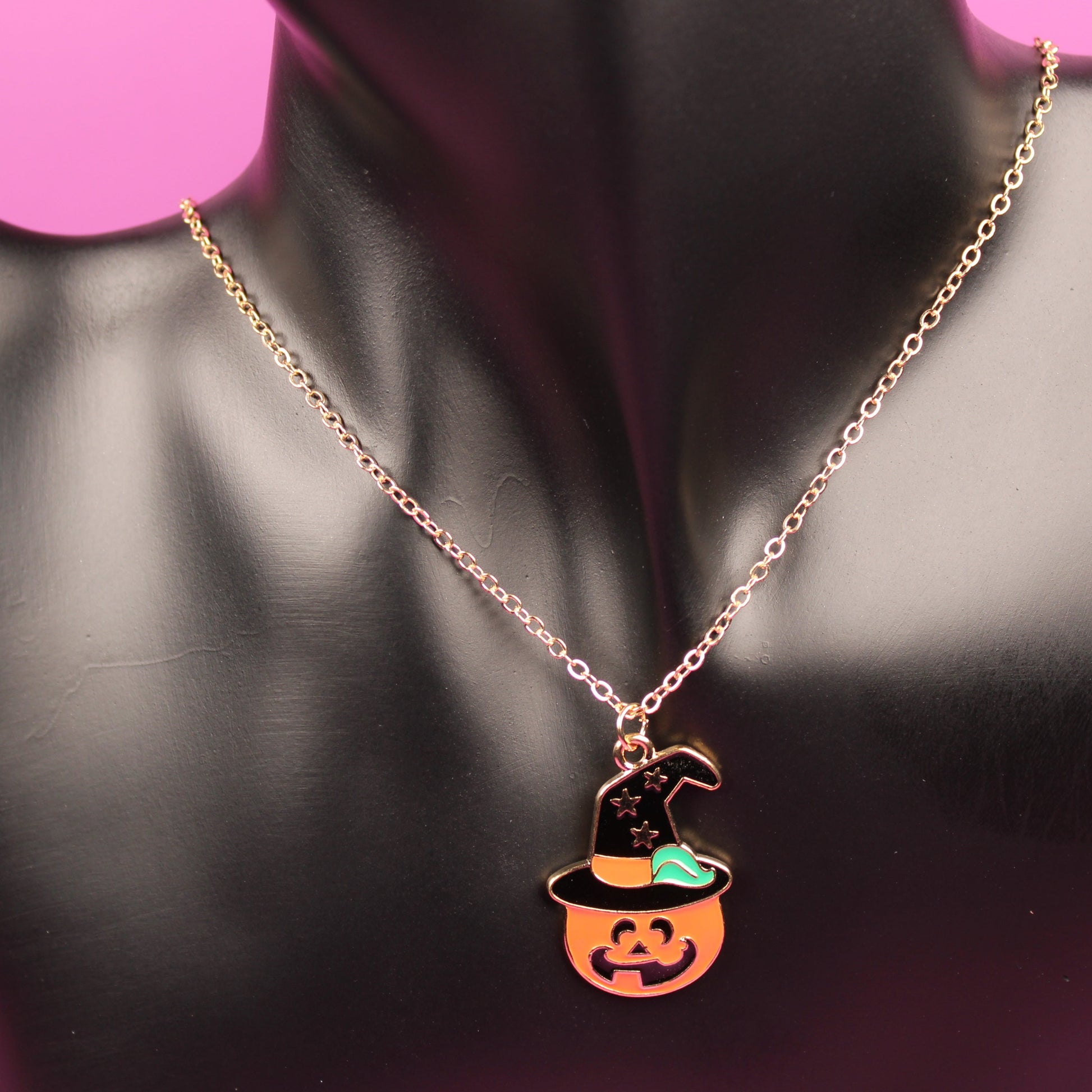 Necklace with a pumpkin pendant on a mannequin bust against a pink background