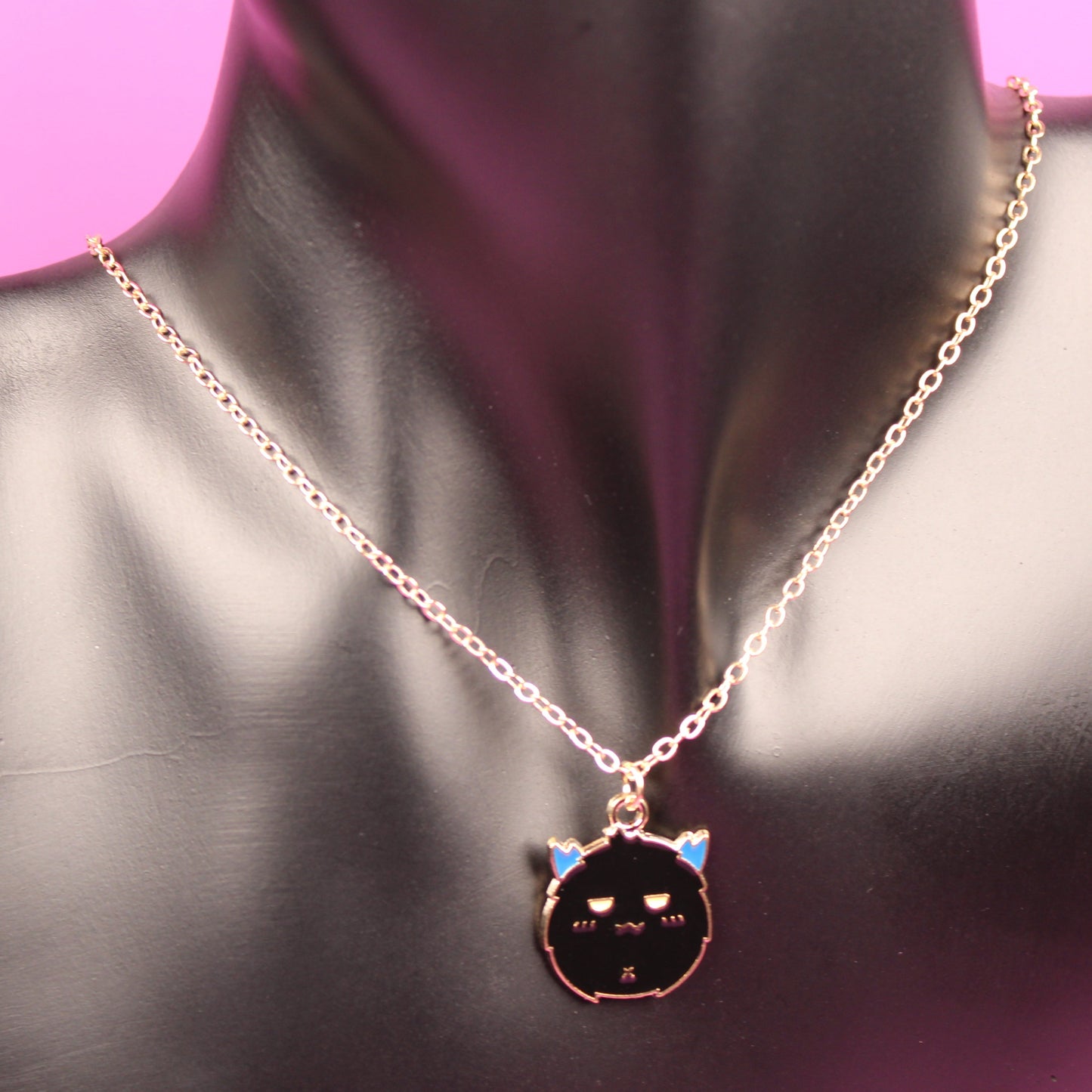Necklace with a cat-shaped pendant on a mannequin bust against a pink background
