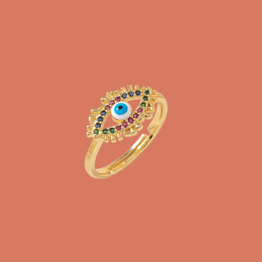Gold ring with colorful gemstones on a white surface with a floral background