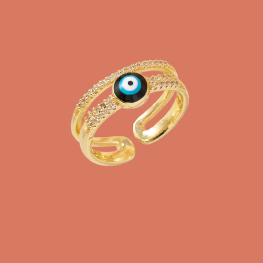 Gold ring with a blue eye design on a white surface